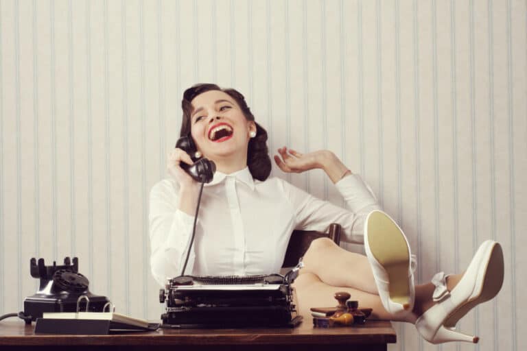 woman with feet up on the desk laughing on the phone