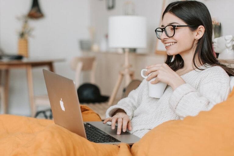 woman holding a mug while using a laptop