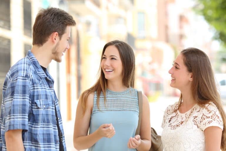 three smiling adults having a quick conversation on the street