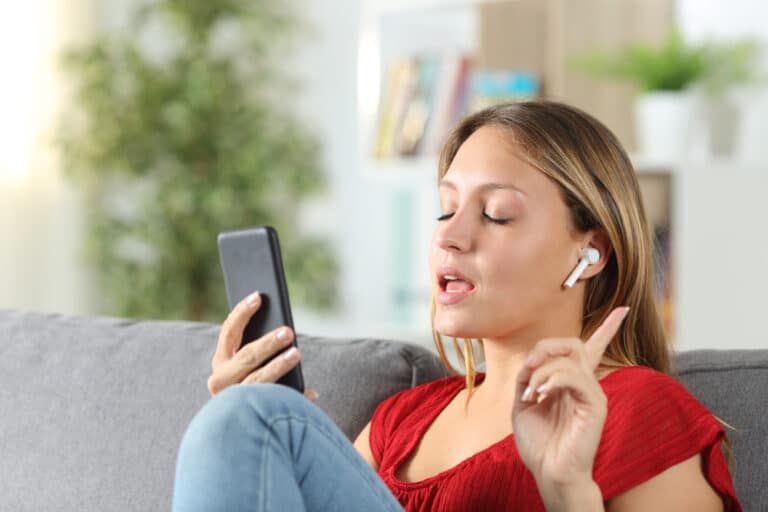 woman with eyes closed and ear phones speaking to her phone
