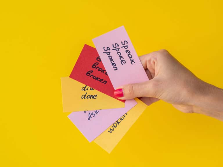 hand holding four foreign language flashcards against yellow background