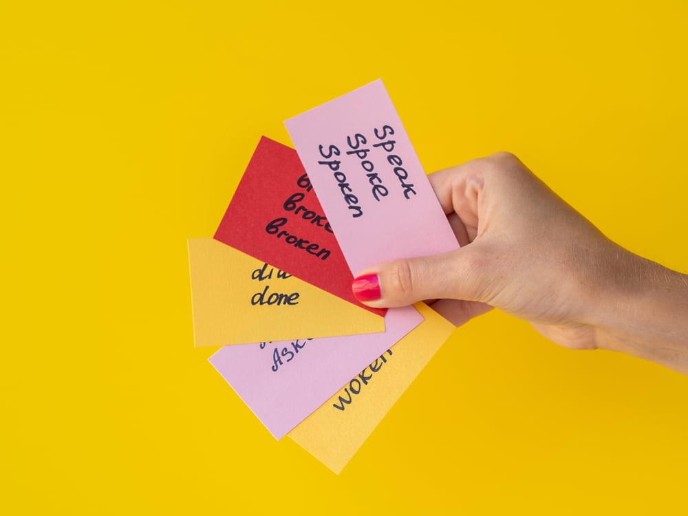 hand holding four foreign language flashcards against yellow background