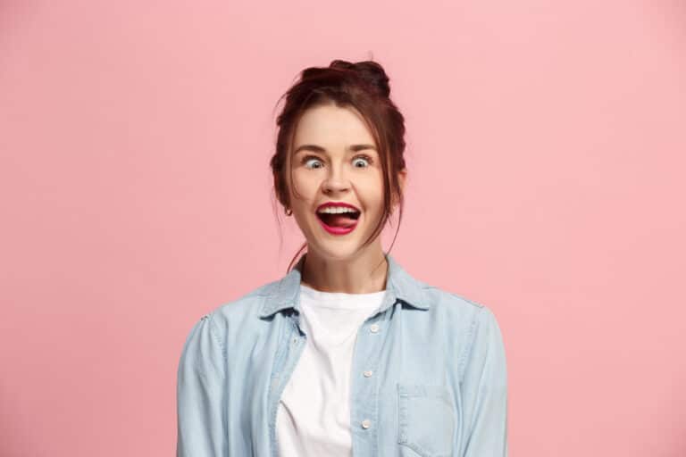 woman making a weird face against a pink background